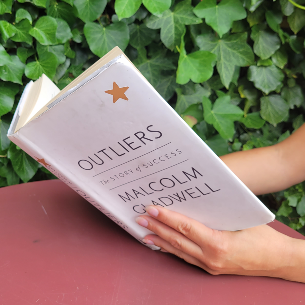 A woman reading Outliers: The Story of Success by Malcolm Gladwell