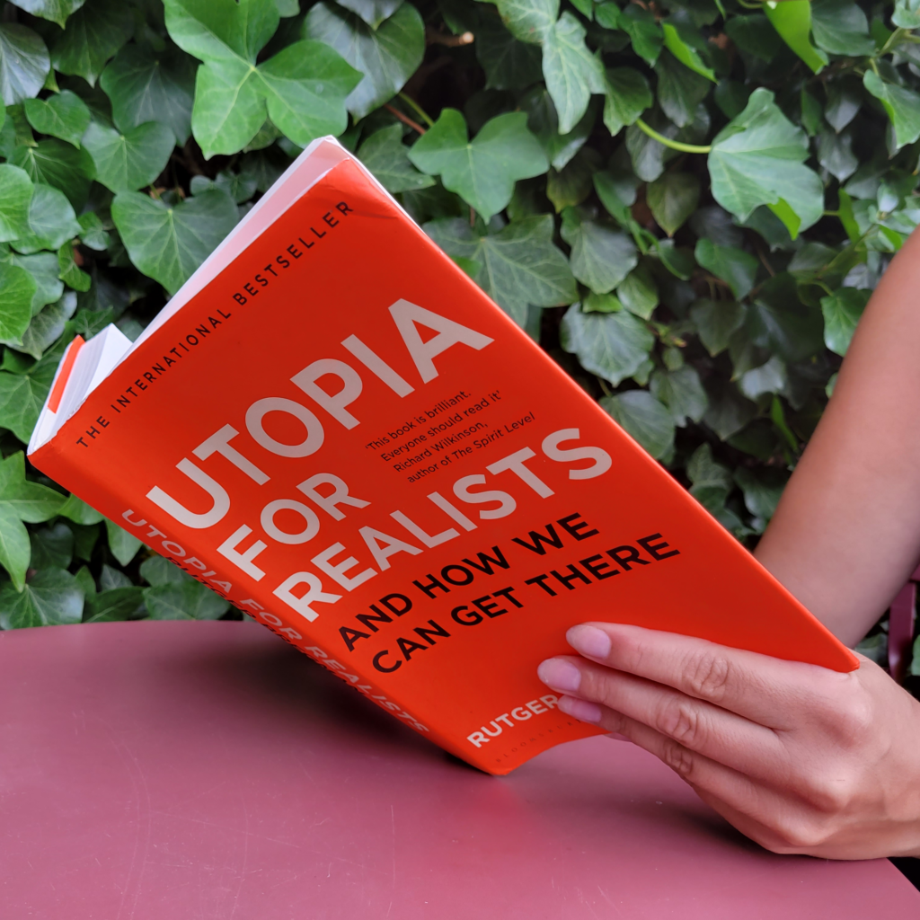 A woman reading Utopia for Realists: How We Can Build the Ideal World by Rutger Bregman